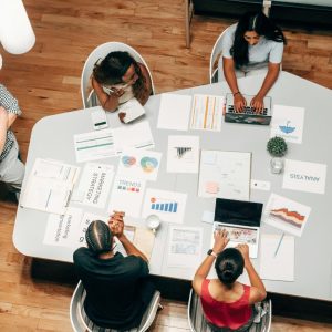 Team collaborates using Facilitate Innovation platform, laptops, and charts in a modern office workspace.