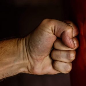 Clenched fist with prominent knuckles punches into red, representing Anger Management branding.