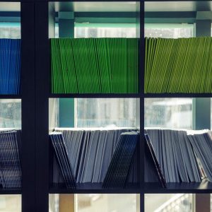 Archiving and Records Management - Self Study manuals stacked on a shelf next to a window.