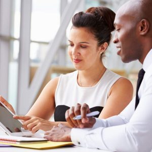 Two people studying Civility In The Workplace course at a desk with tablets and notebooks.