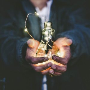 Person holding a glowing clear bulb labeled “Creative Problem Solving - Self Study”.