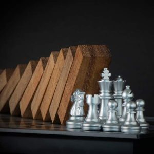 Crisis Management - Self Study: silver chess pieces with toppled dominoes in the background.