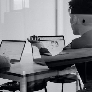 Two people at laptops in a modern office, with text: Delivering Constructive Criticism - Self Study.