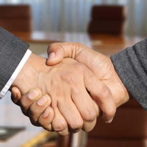 Two professionals shake hands in office setting; Employee Motivation - Self Study program context.