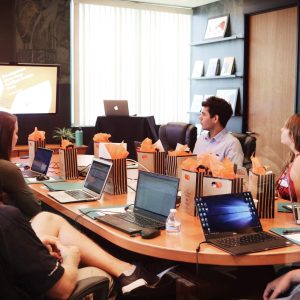 Man presenting “Employee Recruitment - Self Study” to five colleagues at conference table with laptops.