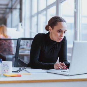 Woman at desk in modern office studies laptop showing “Handling a Difficult Customer” course.