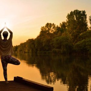 Person in tree pose by a sunset lake, “Improving Mindfulness - Self Study” displayed on screen.