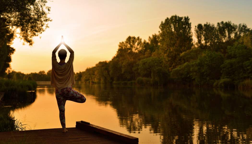 Person in tree pose by a sunset lake, “Improving Mindfulness - Self Study” displayed on screen.