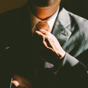 Man in suit adjusting tie, face in shadow with sunlight; text reads “Leadership and Influence - Self Study”.