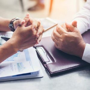 Two people negotiate at a table with papers and a smartphone placed between them.